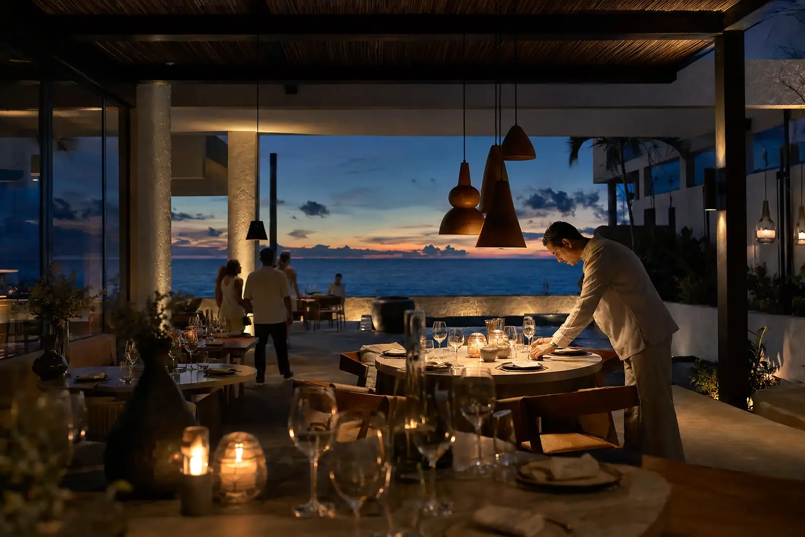 Restaurant team preparing an elegant oceanfront dining experience at dusk