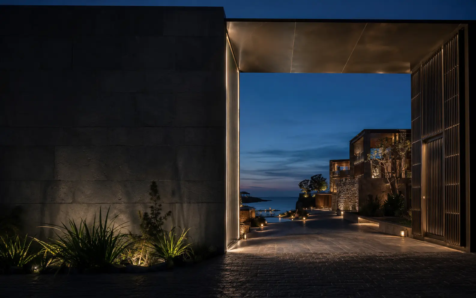 Contemporary coastal resort arrival framed by a monumental portal at blue hour