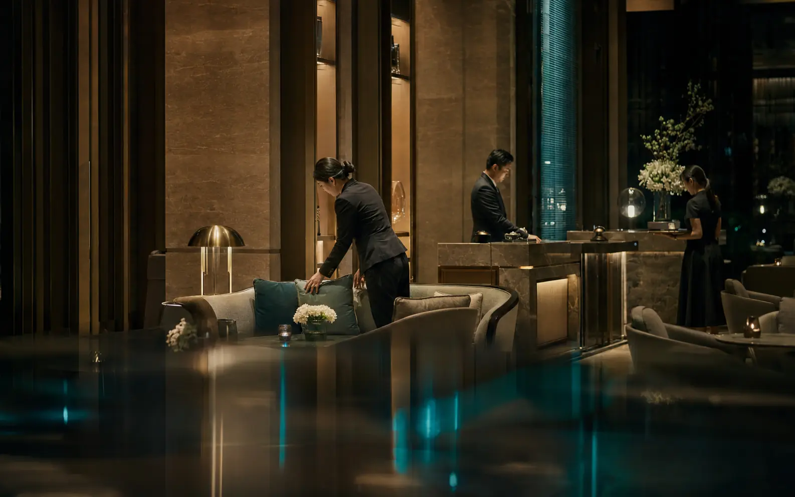 Hospitality team preparing a refined contemporary hotel lobby at night
